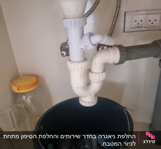 כיור עם צנרת ודלי מתחת לכיור